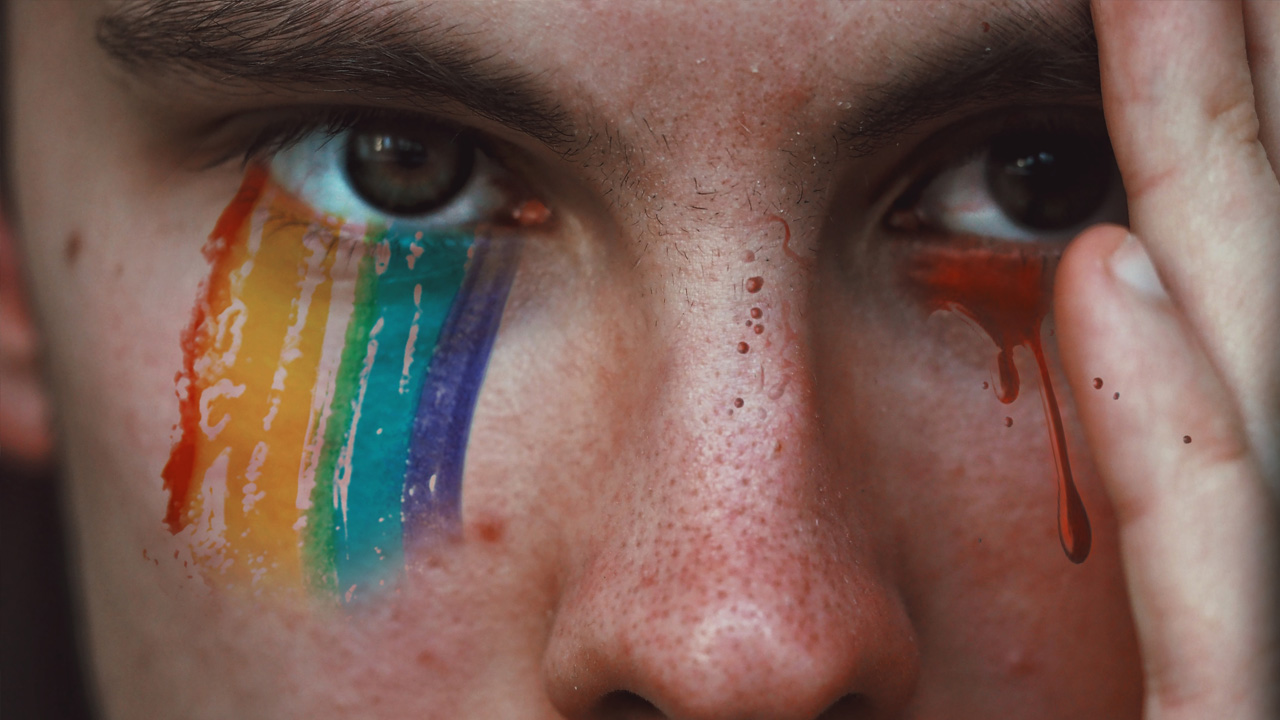 Mensch mit verschmierten Regenbogen im Gesicht