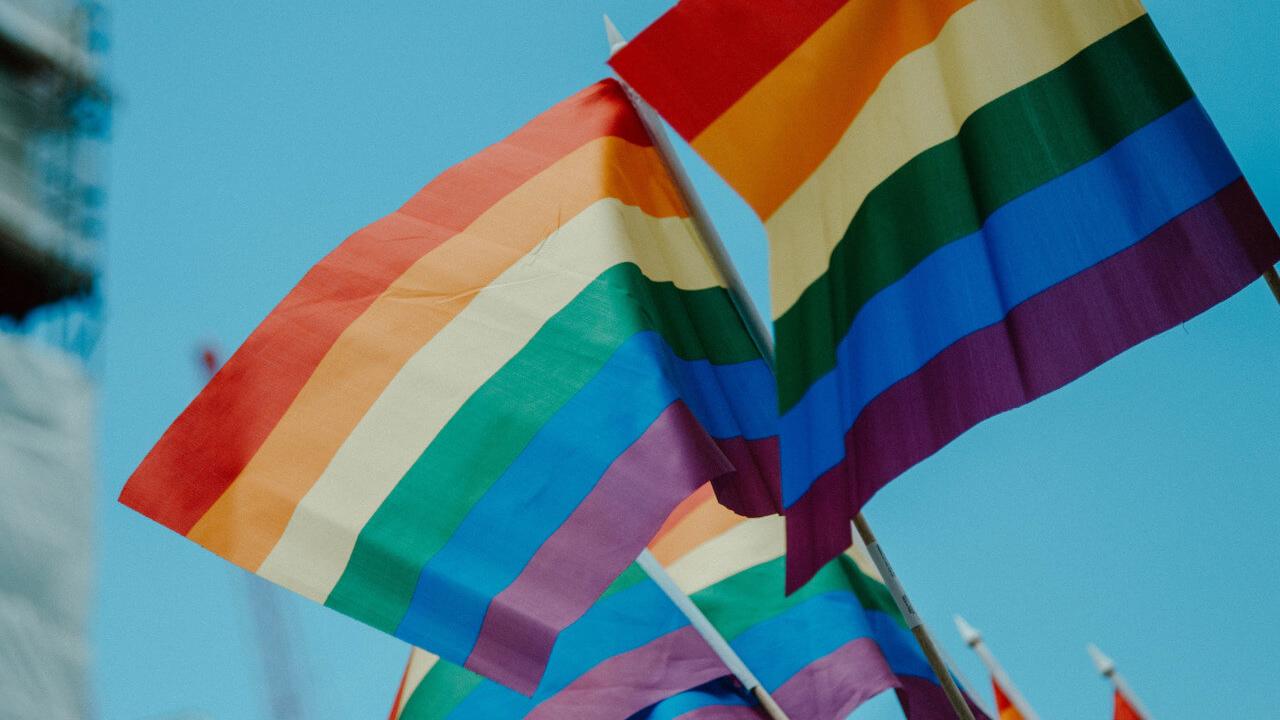 BAMF korrigiert Entscheidung: Geflüchteten-Status für schwulen Ghanaer Kay Mehrere Regenbogenflaggen