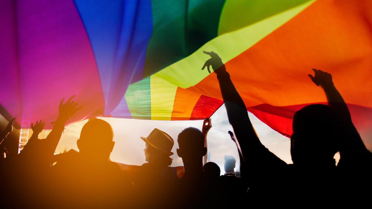 Menschen unter einer großen Regenbogenflagge