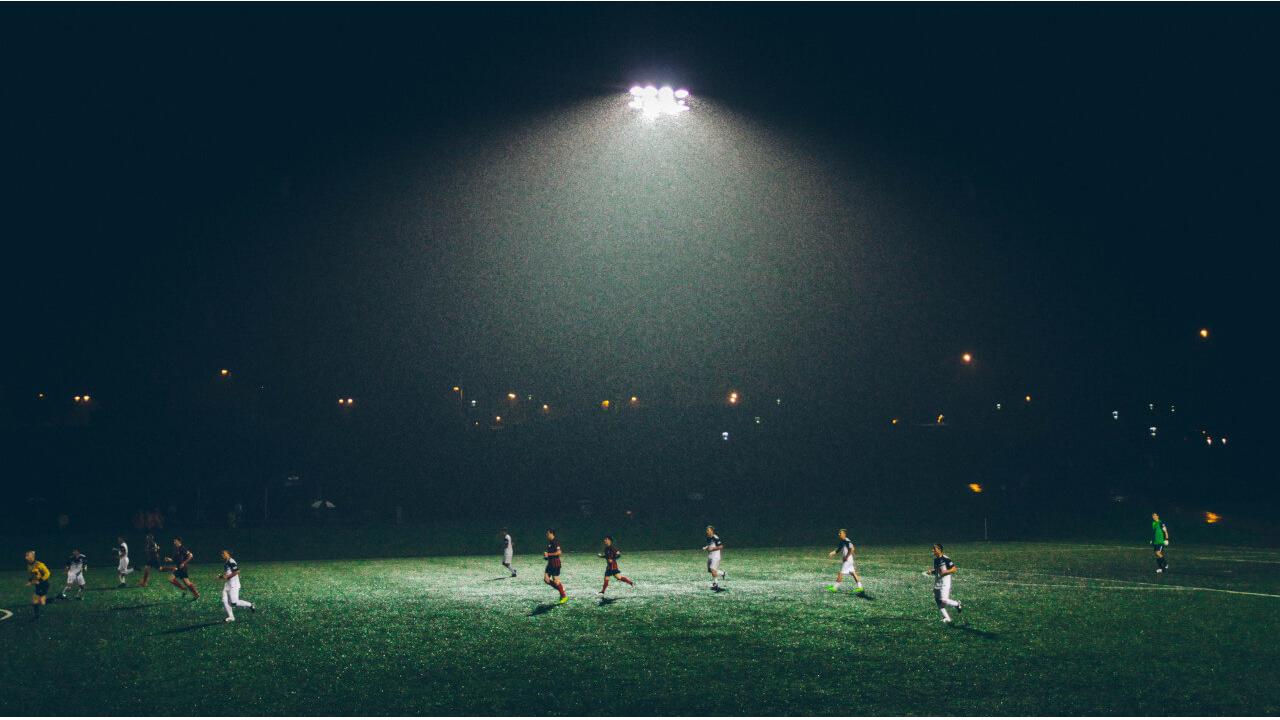 Regenbogenkompetenz im Fußball Fussballspiel im Flutlicht: Symbolbild für Regenbogenkompetenz im Fussball
